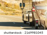 Small photo of Class A Diesel Pusher Recreational Vehicle. RV Motor Coach with Pull Vehicle on a Highway. Travel in a Motorhome.