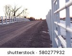 White fence with gravel road. Farm during sunset in winter season.