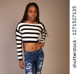 Small photo of Young Black Girl in striped shirt with exposed midriff posing in studio