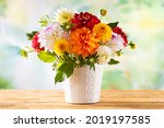 Autumn still life with garden flowers. Beautiful autumnal bouquet in vase on wooden table. Colorful dahlia and chrysanthemum.