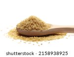 Small photo of Integral uncooked rice pile in wooden spoon isolated on white