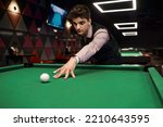 Portrait of young man aiming with billiards cue
