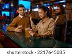Young woman sitting at bar counter rejecting man