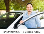 Small photo of Hispanic man smiling and getting into the driver's seat of his car. Male taxi driver about to pick a costumer of a ride sharing app