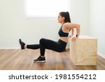 Small photo of Profile of a beautiful active woman in her 30s wearing black activewear and doing tricep dips with a jump box