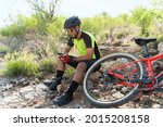 Taking a break after working out outdoors. Male athlete resting while texting and looking at social media on his smartphone next to a mountain bike