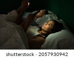 Gorgeous latin woman resting next to her boyfriend on a dark night and texting on her smartphone