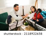 Small photo of Writing the lyrics of a song. Attractive woman and man composing a new song on a music sheet while playing instruments