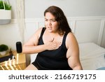 Small photo of Unhealthy obese woman putting a hand in her chest and having heart problems or suffering from tachycardia