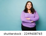 Small photo of Beautiful mexican obese woman with her arms crossed smiling against a studio background with copy space
