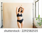 Smiling plus size woman in black underwear with her arms above her head feeling a lot of self love embracing body positivity