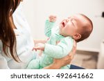 Portrait of a cute newborn baby crying in front of her mother while she holds her and tries to comfort her
