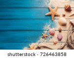 Summer time concept with sea shells and starfish on a blue wooden background and sand