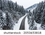 car driving on asphalt road through the winter snowy forest . Drone top view of frozen winter forest. Areal view.