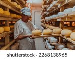 Small photo of A worker at a cheese factory sorting freshly processed cheese on drying shelves