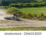 Small photo of A professional motocross rider experiences an unfortunate fall from their motorcycle on a forest trail, highlighting the dangers of off-road racing.