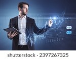 Attractive businessman with tablet using creative candlestick trading graph on blurry office background. Selling and buying stocks, market, investment and financial growth concept