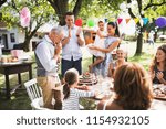 Small photo of A senior man with an extended family looking at the birthday cake, crying.