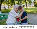 Small photo of Grandchild surprised her grandmother with a birthday present in the park. Lifestyle, family concept