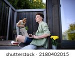 Happy young couple with laptop resting outdoors in a tiny house, weekend away and remote office concept.