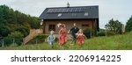 Small photo of Happy family running near their house with solar panels. Alternative energy, saving resources and sustainable lifestyle concept.