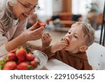 Grandmother giving homegrown strawberries to her little grandson.