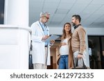 Small photo of Pregnant woman and husband talking to obstetrician in hospital. Admitting woman in labor to maternity ward, planned cesarean section delivery.
