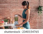 Shot of beautiful sporty woman doing healthy smoothie while listening to music in the kitchen.