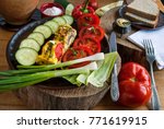Small photo of A vegetarian breakfast with sliced tomatoes, cucumbers, peppers and onions served on a wooden table in a rustic style and lit by hard, contravene light from the window.