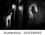 Silhouette of a man in a coat and hat in a dark alley on a rainy night. theme of violence and cruelty. blur effect
