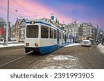 Tram driving in snowy Amsterdam in the Netherlands at sunset