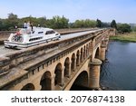 Small photo of BEZIERS, FRANCE - OCTOBER 3, 2021: Boat across river Orb bridge on historic Canal du Midi in France. Canal du Midi is a UNESCO World Heritage Site.