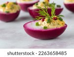 Small photo of A beet juice soaked devilled egg garnished with chives, dill and peppercorns.