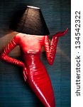 Small photo of Woman shaped red floor lamp with shader on blue brushed background