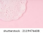 White cleanser foam drop on pink background. Soap, shower gel, shampoo foam texture closeup