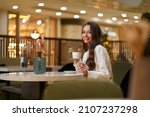 Young beautiful stylish woman in white blazer with cup od coffee sitting in restaurant