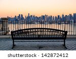 Bench in park and New York City midtown Manhattan at sunset with skyline panorama view over Hudson River
