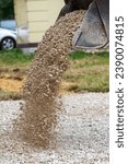 Small photo of a bulldozer pours macadam from a bucket onto the ground at a construction site - close-up view.