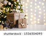 christmas and new year background - gift boxes and stars near decorated christmas tree and copy space over white wall with garland lights