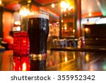 Glass of dark beer with candle in pub setting