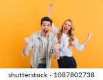 Portrait of cheerful people man and woman in basic clothing smiling and clenching fists like winners or happy people isolated over yellow background