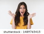 Image of excited brunette woman wearing casual t-shirt surprising and throwing up her hands isolated over white background