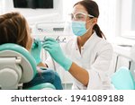 European mid pleased dentist woman in face mask working in dental clinic