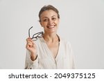 European mid woman holding eyeglasses smiling at camera isolated over white background