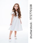 Full length of beautiful little girl in dress standing and posing over white background