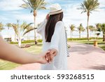 Follow me. Pretty young woman in hat holding hand and leading her friend on summer resort