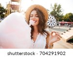 Close up portrait of a smiling young girl eating cotton candy at amusement park