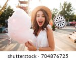 Close up portrait of a smiling excited girl holding cotton candy at amusement park