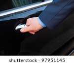 Chauffeur's hand opening passenger door on limousine