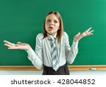 Small photo of What's amiss? Perturbed girl near blackboard with divorced his hands